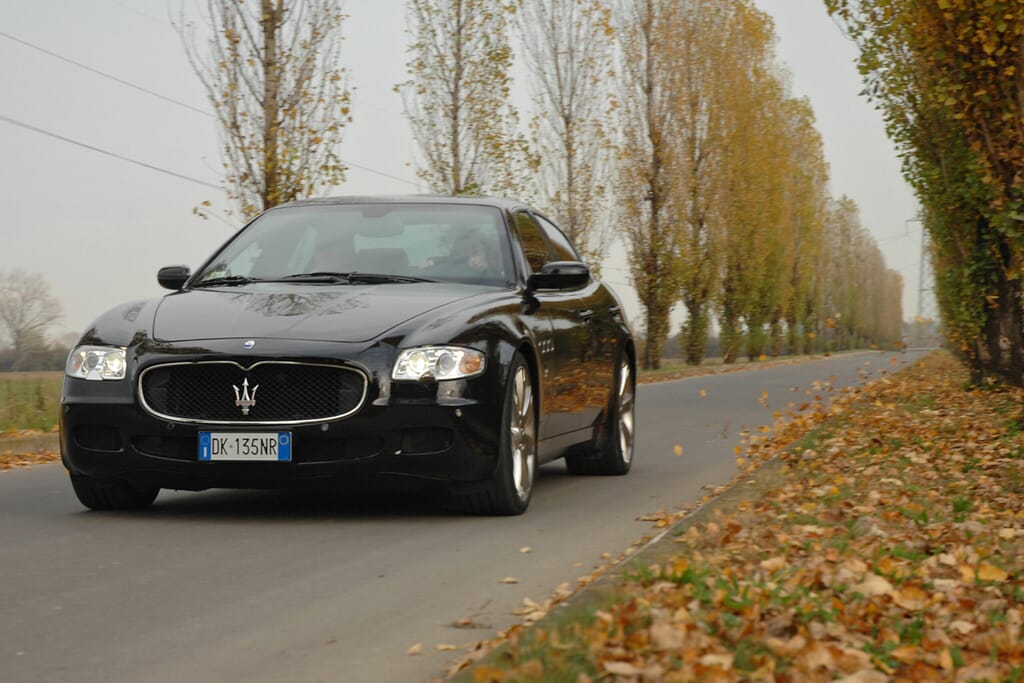 Black-Maserati-Quattroporte-V-driving-tree-lined-road
