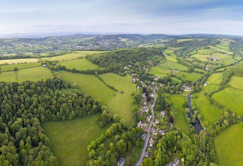 Dramatic aerial view of gently rolling patchwork farmland with pretty wooded boundaries, in the beautiful surroundings of the Cotswolds, England, UK. Stitched panoramic image.